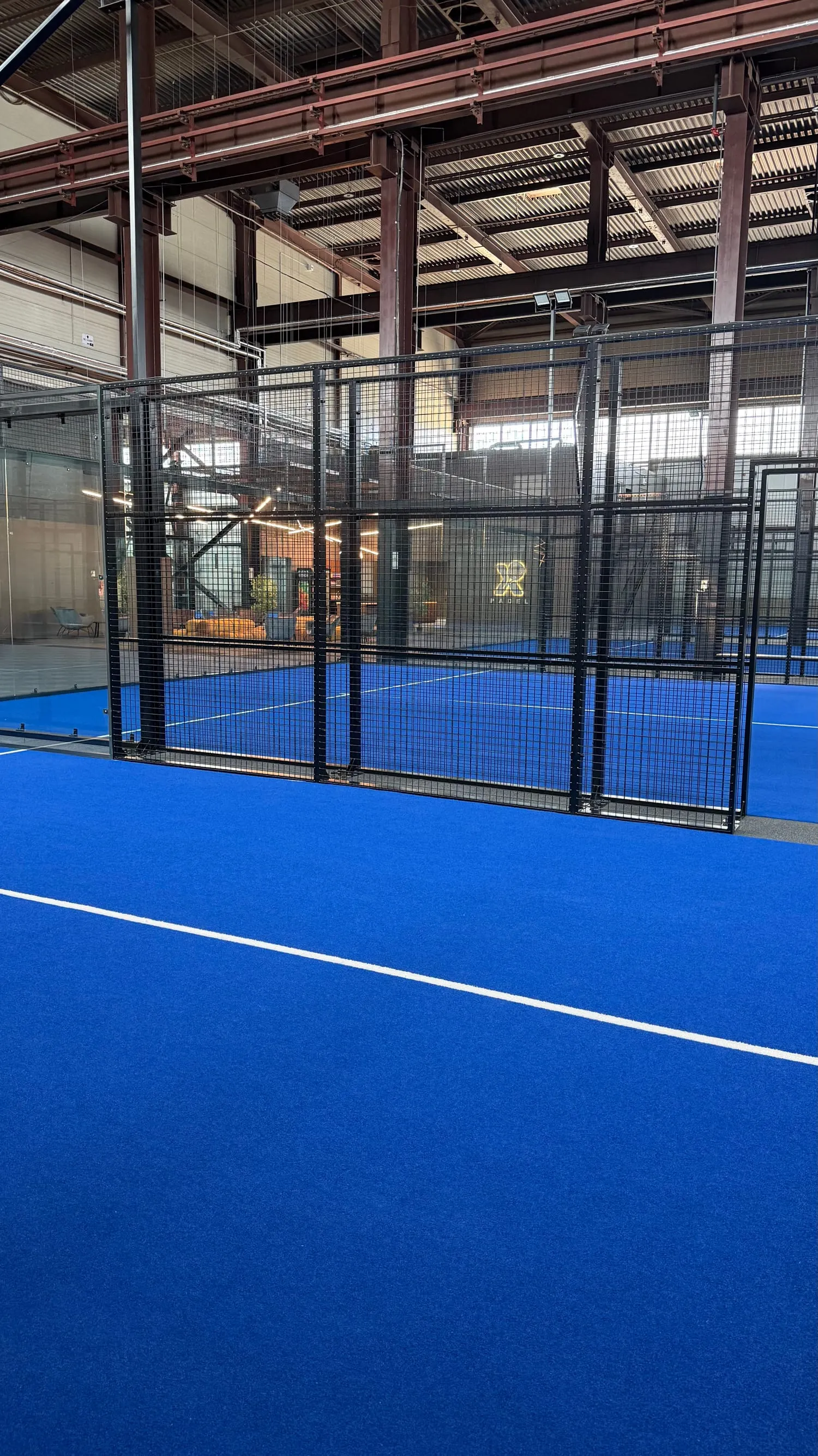 Padel laukuma zilais segums un stikla siena